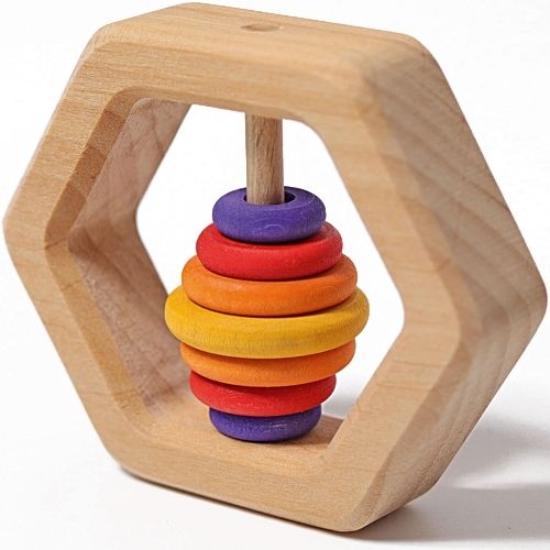 Grimm's houten zeshoekige rammelaar met regenboogkleurige ringen, schuin van voren gefotografeerd.