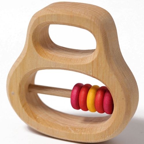 Grimm's houten rammelaar en bijtring met rode en gele ringetjes, schuin van voren gefotografeerd.