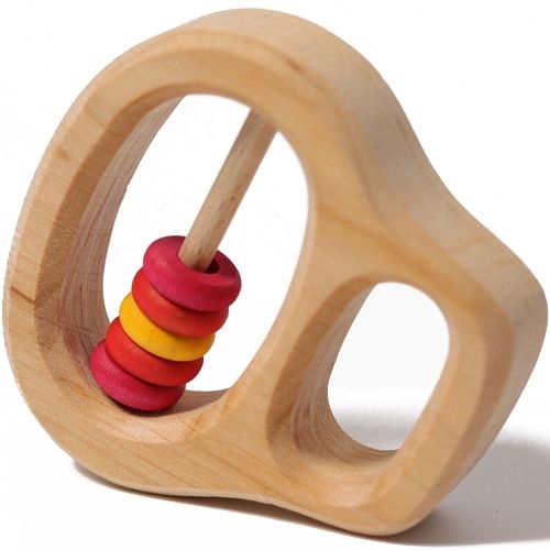 Grimm's houten rammelaar en bijtring met rode en gele ringetjes, schuin van bovenaf gefotografeerd.