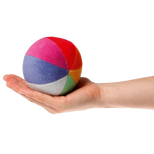 Een hand houdt de Grimm's stoffen regenboogbal rammelaar vast om de grootte te tonen.
