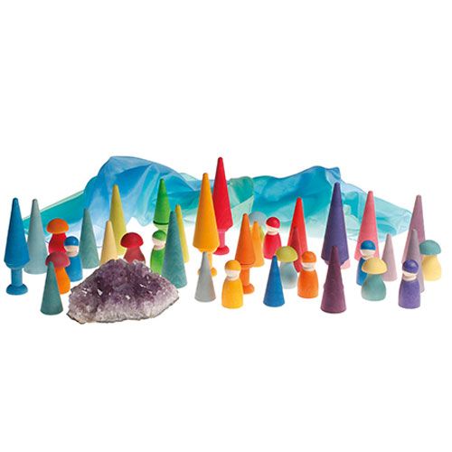 Grimm's regenboog bos houten speelgoedset met veelkleurige kegels, poppetjes en een kristal, opgesteld als een fantasielandschap.