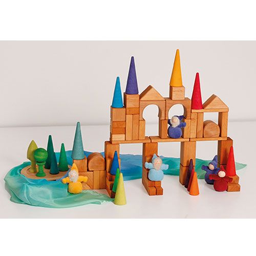Grimm's houten bouwspeelgoedset met een kasteel, veelkleurige kegels en poppetjes, opgesteld als een fantasielandschap met water.