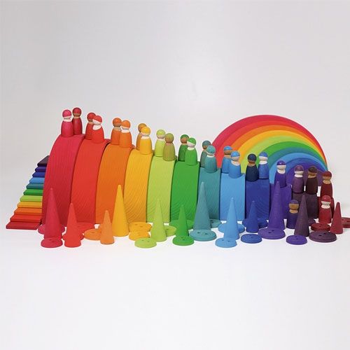 Een uitgebreide collectie grimm's houten speelgoed, waaronder de regenboog stapeltoren, peg dolls en kegels in alle kleuren van de regenboog.