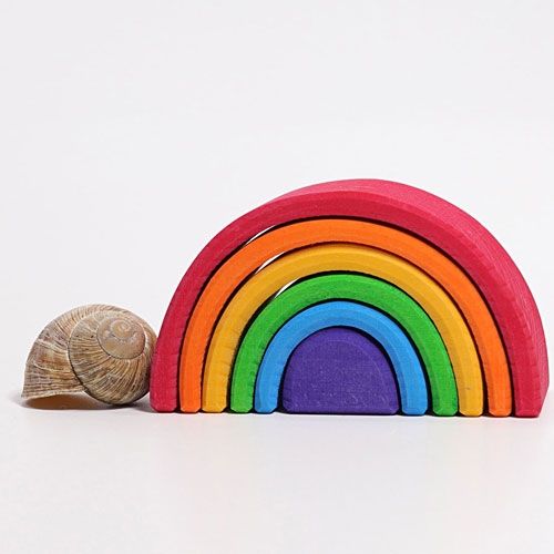 Grimm's houten regenboog stapelspeelgoed met zes bogen, naast een slakkenhuisje voor schaal.