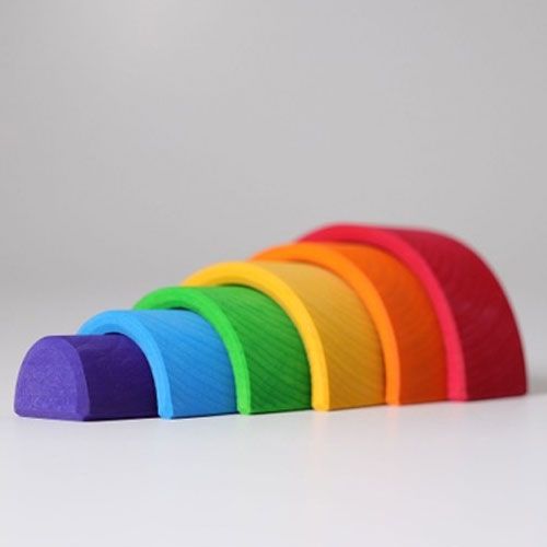 De zes gekleurde houten bogen van het regenboog stapelspeelgoed liggen naast elkaar op een rij.