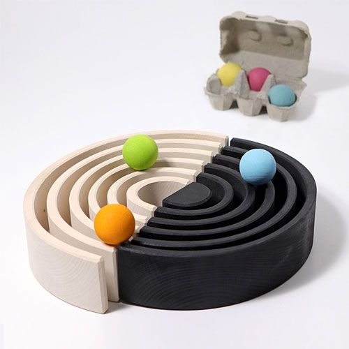 Grimm's houten regenboog stapeltoren met monochrome bogen in een cirkel, met gekleurde ballen en eieren.