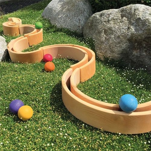grimm's houten bogen als knikkerbaan op gras met gekleurde ballen en rotsen.