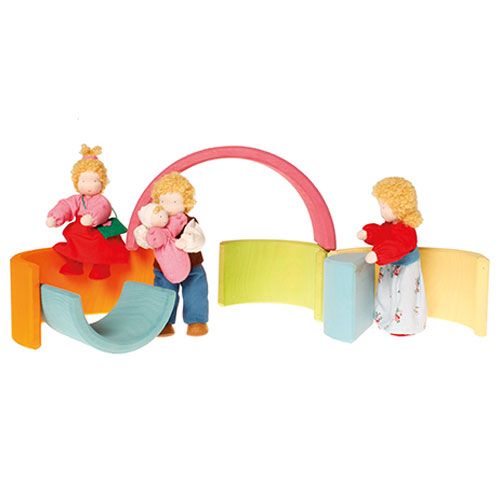Drie poppetjes spelen met de grimm's houten regenboog stapeltoren, waarbij de bogen als speeltoestellen en muren worden gebruikt.