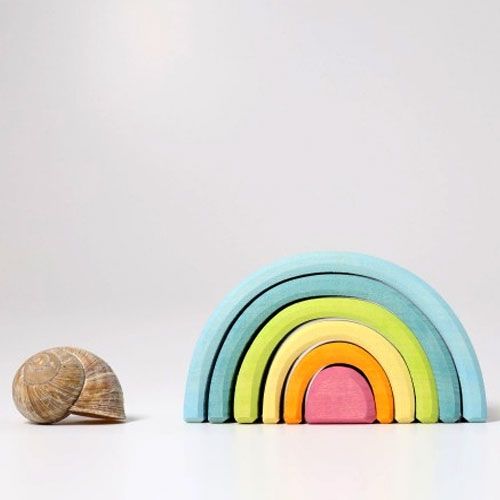 Grimm's houten regenboog stapeltoren met 6 pastelkleurige bogen naast een slakkenhuis voor schaal.