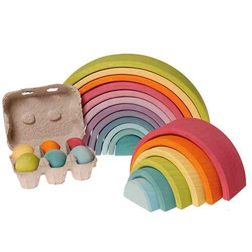 Collectie grimm's regenboog stapeltorens en een doosje met zes pastelkleurige houten eieren.