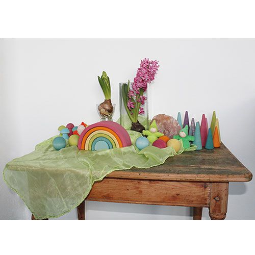 Een tafel gedecoreerd met grimm's houten speelgoed, waaronder de pastel regenboog stapeltoren en hyacinten.