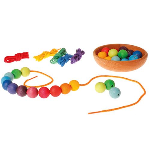 Grimm's rijgspeelgoed met een houten kom vol kleurrijke kralen en een rijgtouwtje met regenboogkleurige kralen.