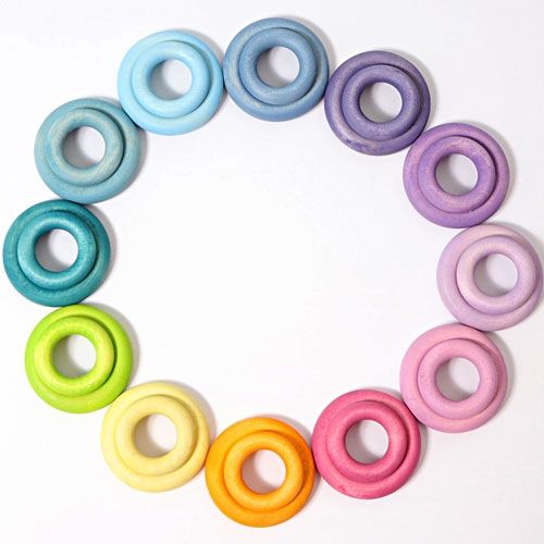 grimm's pastelkleurige houten ringen, per twee gestapeld, in een cirkel op een witte achtergrond.