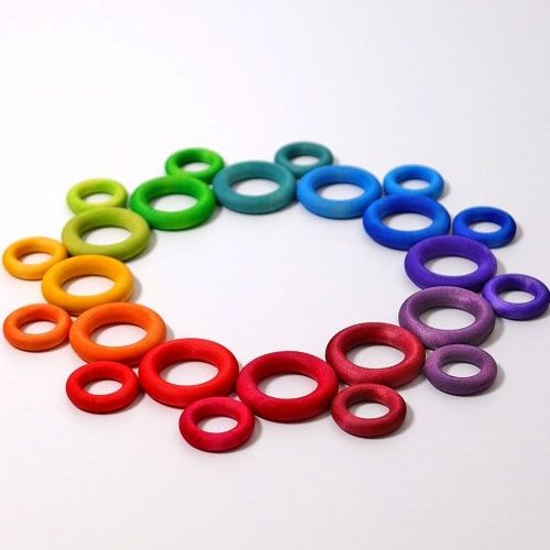 grimm's regenboog houten ringen in verschillende maten, gerangschikt in een cirkel op een witte ondergrond.