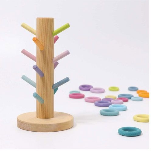 grimm's houten sorteerkapstok met pastelkleurige pinnen en losse ringen op de grond.