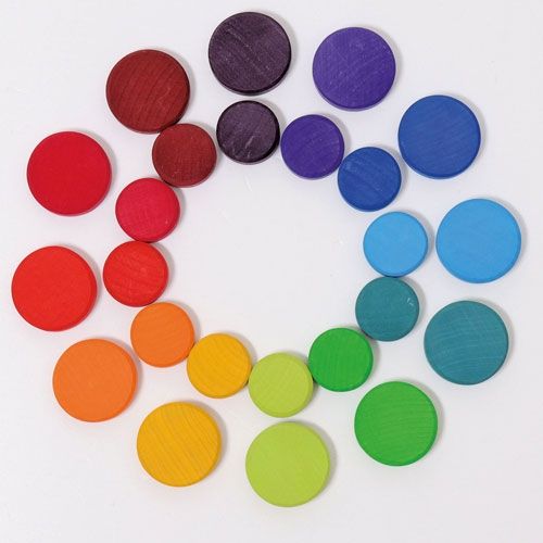 Een bovenaanzicht van grimm's houten sorteermunten voor babyspeelgoed, gerangschikt in een regenboogkleurencirkel.