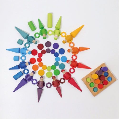 Een bovenaanzicht van een collectie grimm's houten sorteer- en stapelspeelgoed in regenboogkleuren, inclusief munten, peg dolls en een sorteerplankje.