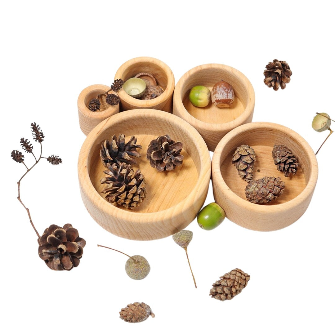 Grimm's houten stapelbakjes naturel gevuld met dennenappels en eikels, omringd door natuurlijke materialen.