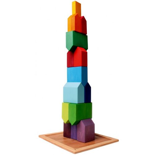 Grimm's houten bouwblokken in de vorm van kleine, veelkleurige huisjes gestapeld tot een hoge toren op een houten plaat.