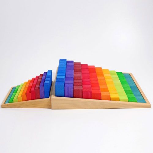 Twee sets Grimm's houten bouwblokken in regenboogkleuren, gesorteerd in houten bakken.
