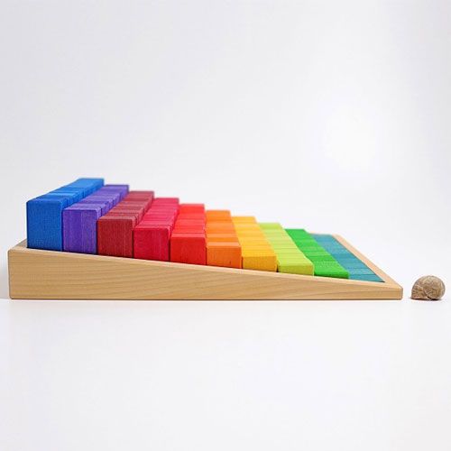 Grimm's houten bouwblokken in een regenboogkleurig getallenland, gesorteerd in een houten bak, met een slakkenhuisje voor schaal.