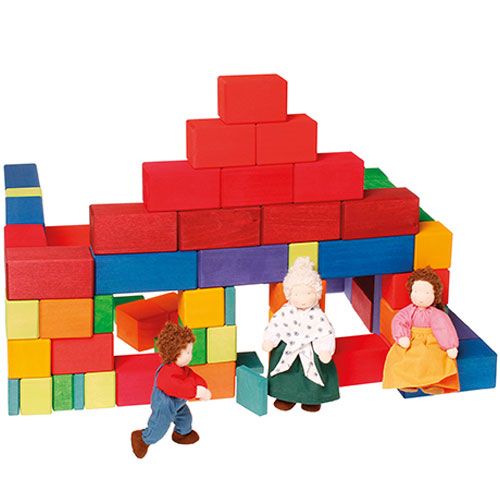 Grimm's houten bouwblokken vormen een huis met drie stoffen poppen ervoor.