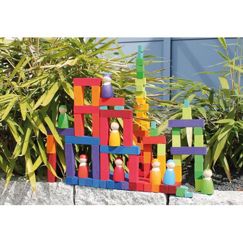 Een kleurrijke constructie van grimm's houten bouwblokken en peg dolls, opgebouwd in een tuin.