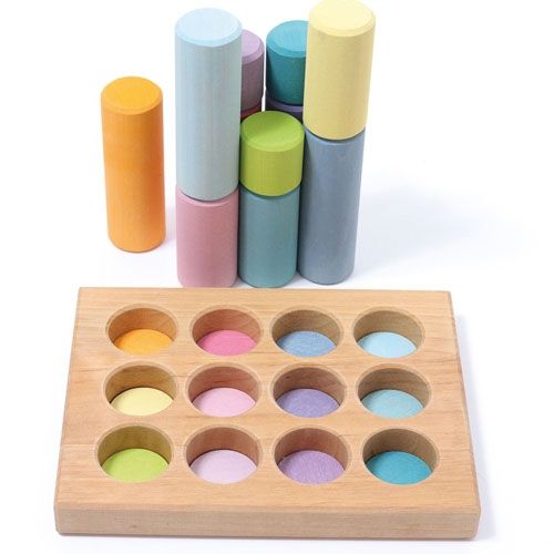 grimm's houten sorteerbord met pastelkleurige schijven en gestapelde cilindervormige blokken.