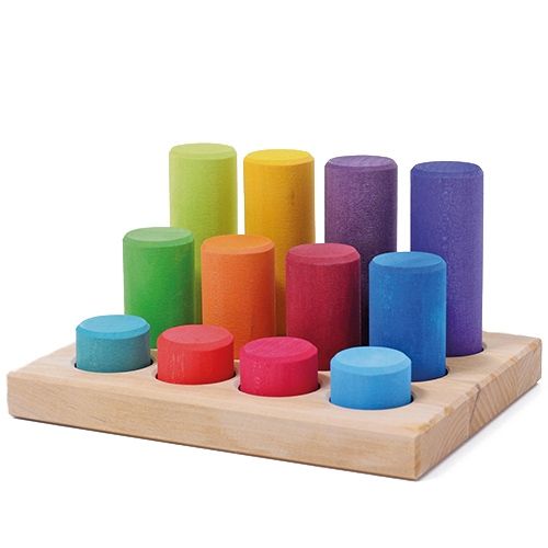 grimm's regenboog stapelrollers van hout in een houten basis, gesorteerd op hoogte.