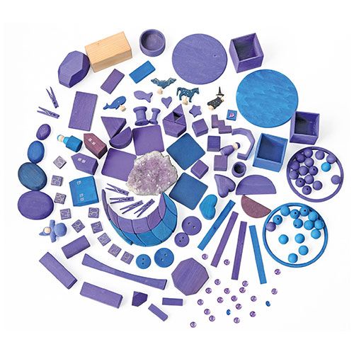 Een bovenaanzicht van een grote collectie grimm's houten speelgoed in paarse en blauwe tinten, inclusief kiezelstenen, blokken en figuren.