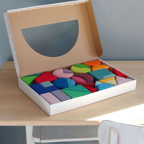 De verpakking van het Grimm's stapelspel met veelkleurige houten blokken in een open kartonnen doos.