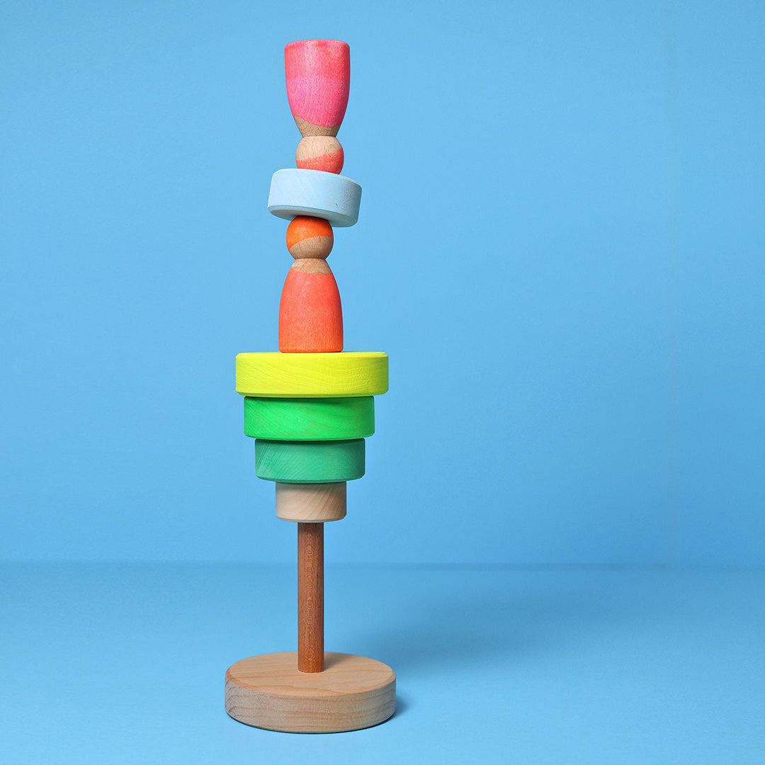 Grimm's houten stapelspeelgoed met diverse gekleurde vormen en poppetjes creatief gestapeld op een blauwe achtergrond.