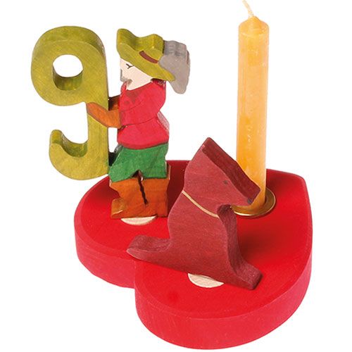 grimm's rode hartvormige tafeldecoratie met een houten figuur, een hond en een brandende kaars.