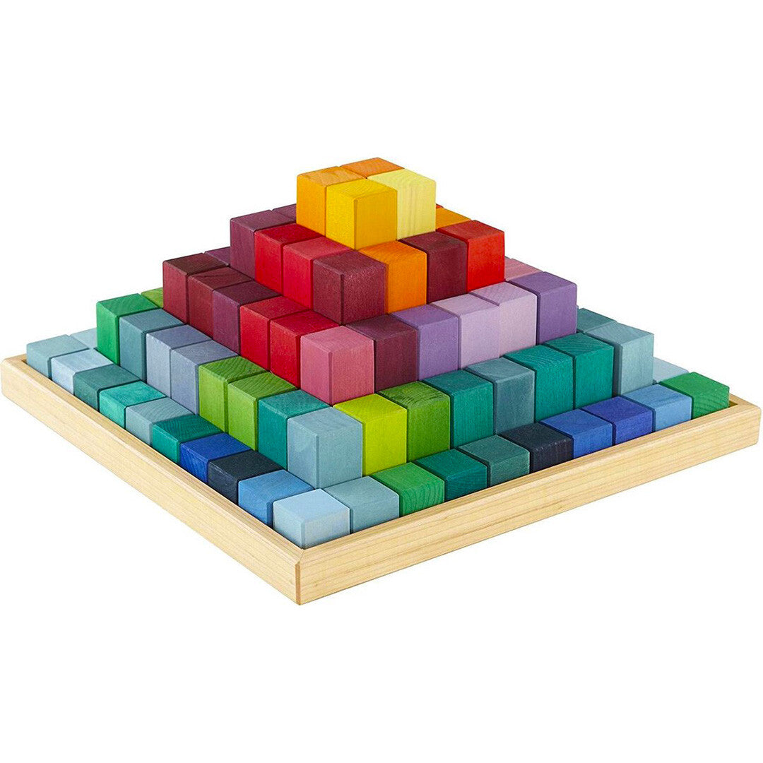 Grimm's houten trappiramide van veelkleurige regenboogblokken in een houten bak, schuin van bovenaf gefotografeerd.