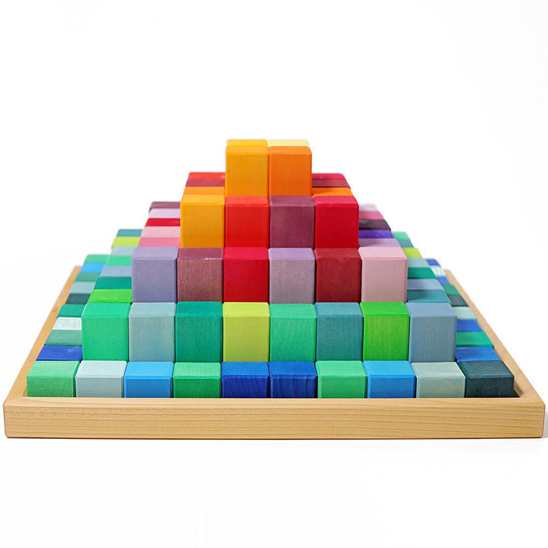 Grimm's houten trappiramide van veelkleurige regenboogblokken in een houten bak, van voren gefotografeerd.