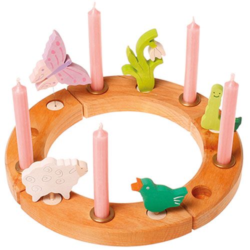 Grimm's houten verjaardagsring versierd met roze kaarsen en houten figuren van een vlinder, schaap, vogel en planten.