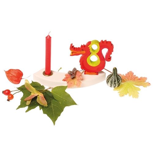 Een segment van de grimm's verjaardagsring met een rode kaars, een rode draak en herfstdecoratie.