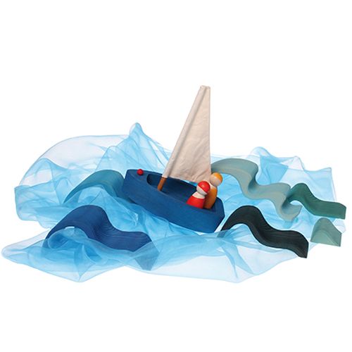 grimm's houten speelgoedboot met twee poppetjes, omringd door blauwe en groene stoffen golven en houten golfblokken.
