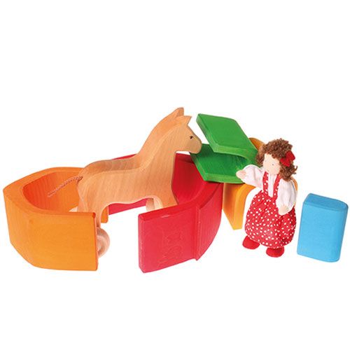 Grimm's houten huisvormen voor peuters, opgesteld als omheining voor een houten paard met een stoffen pop.