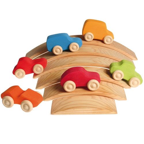 Zes grimm's houten speelgoedauto's in verschillende kleuren op een stapel houten bogen.