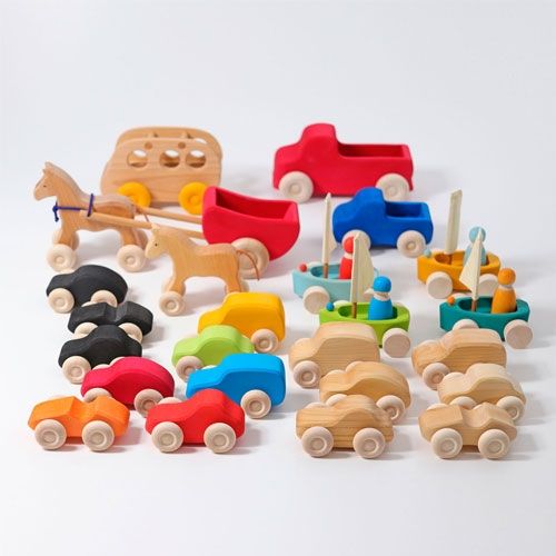 Een grote collectie grimm's houten speelgoedvoertuigen in diverse kleuren en modellen.