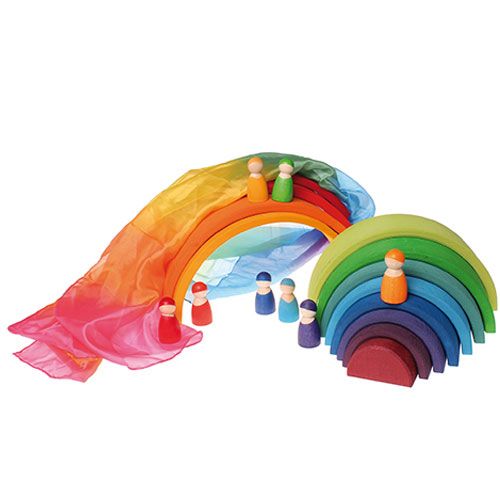 Grimm's zijden regenboog speeldoek gedrapeerd over een houten regenboog stapelaar met houten poppetjes.