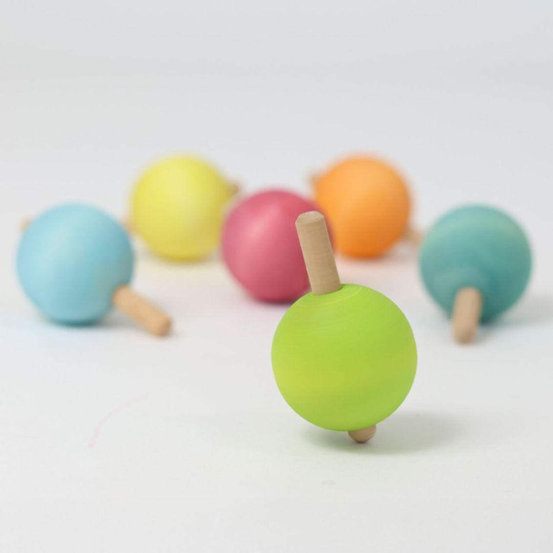 Grimm's lichtgroene houten tol in de voorgrond, met andere pastelkleurige tollen onscherp op de achtergrond.