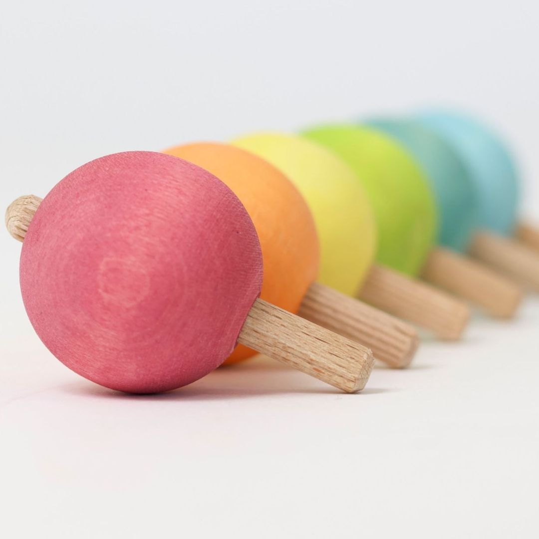 Grimm's zes houten tollen in pastelkleuren op een rij, met de roze tol vooraan.