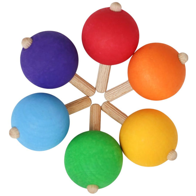 grimm's houten draaitollen in regenboogkleuren liggen in een cirkel, van bovenaf gezien.