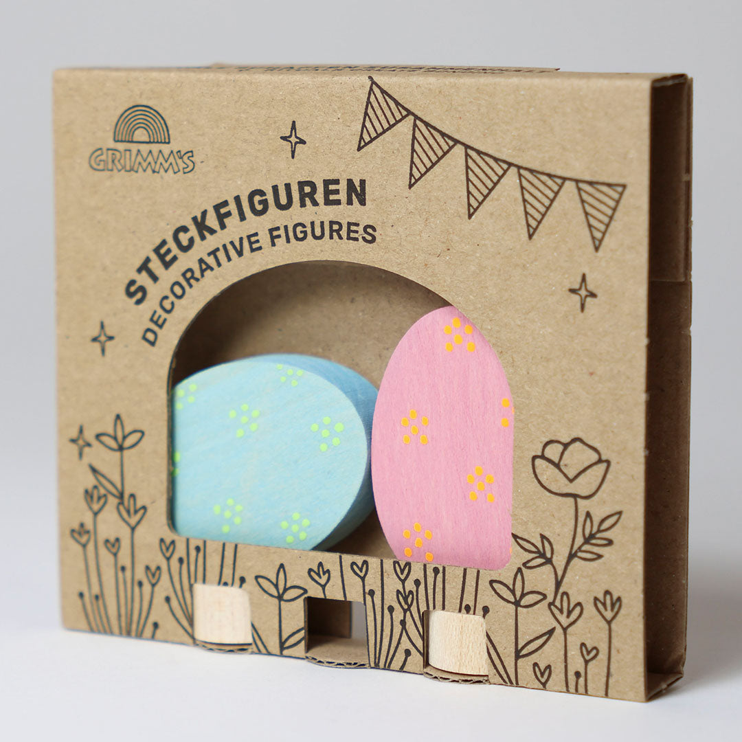 De verpakking van de Grimm's houten paaseieren decoratie figuren, met een roze en een blauw ei zichtbaar.
