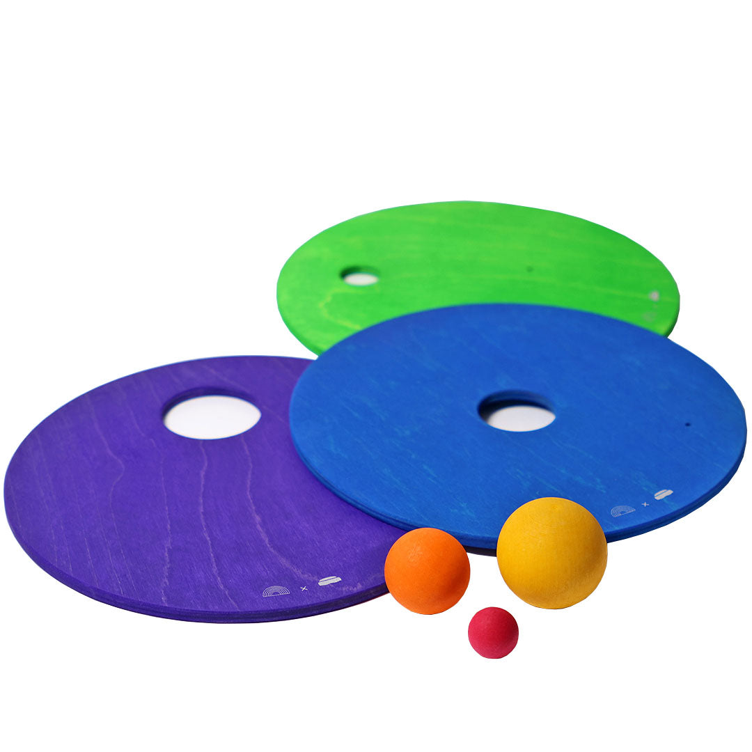 Drie platte, ronde grimm's houten schijven in paars, blauw en groen met drie kleine houten ballen.