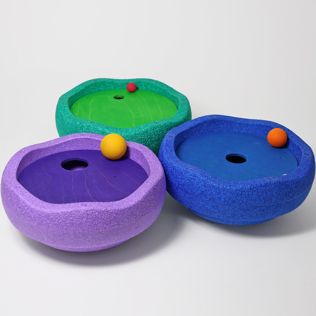 Drie grimm's x stapelstein rolling discs in paars, blauw en groen, elk met een houten schijf en een bal erin.