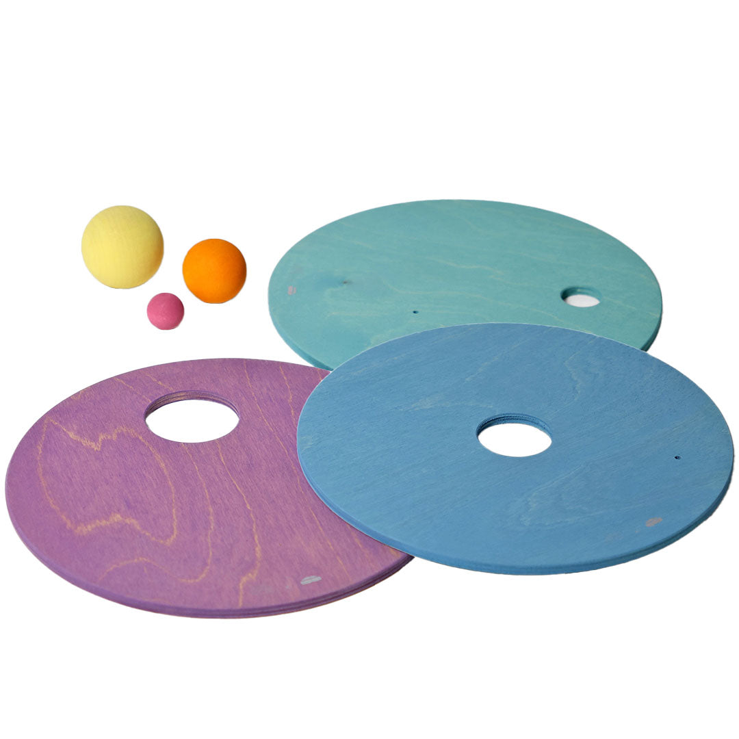 Drie grimm's houten rolling discs in pastelkleuren paars, lichtblauw en turquoise, met drie kleine balletjes ernaast.