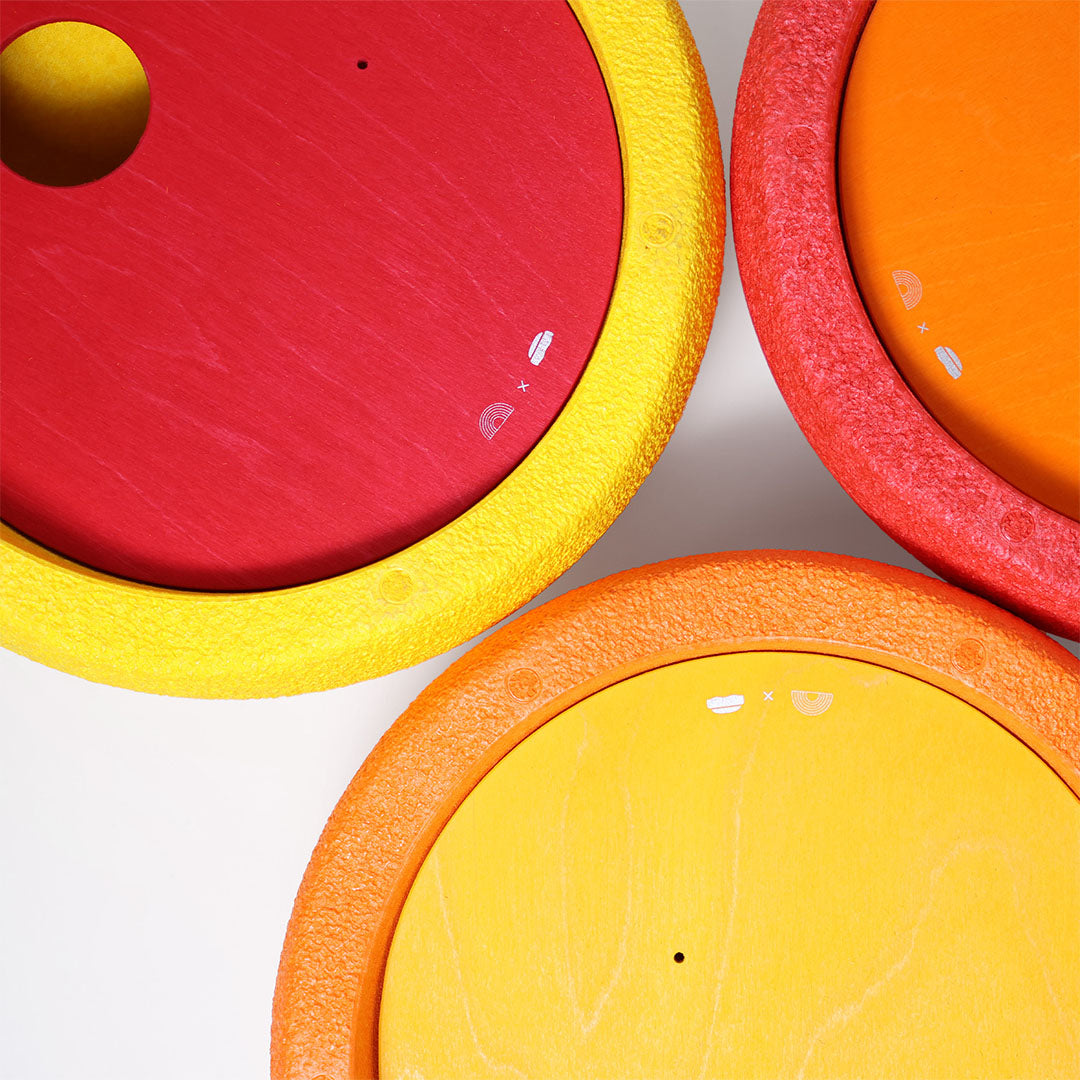 Detailfoto van drie grimm's rolling discs in rood, geel en oranje met hun gestructureerde randen.